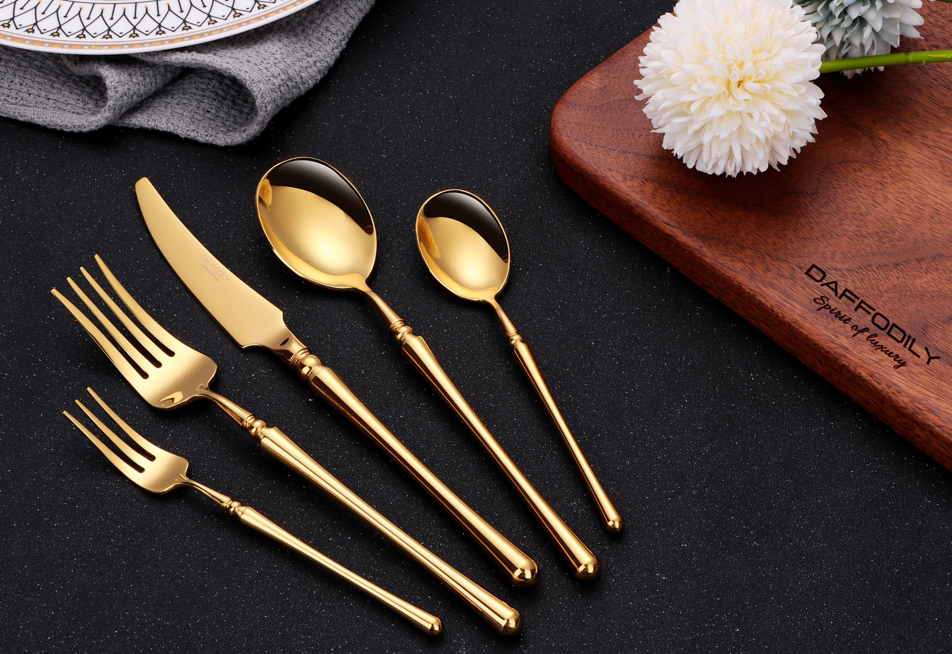 Talin luxury cutlery set with gold finish on wooden board and white flowers